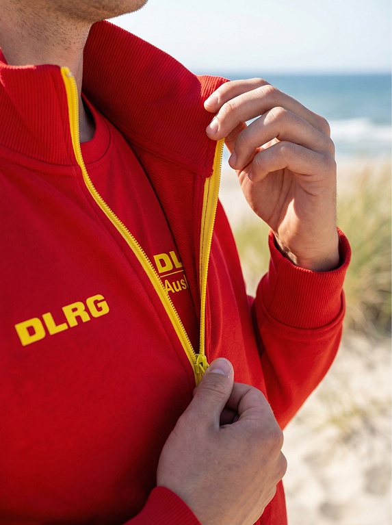 Person am Strand in roter DLRG Jacke